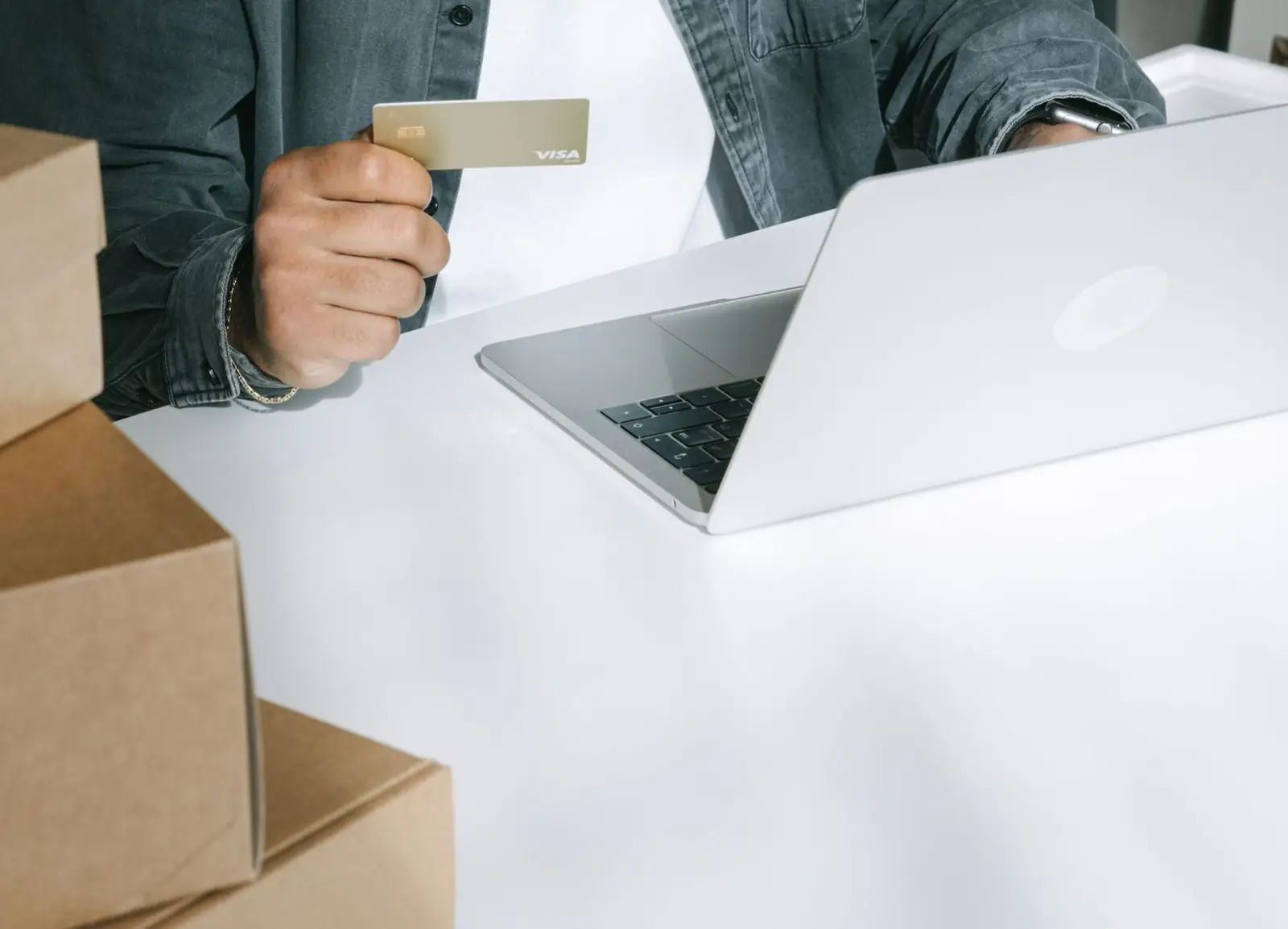 Managing online orders on a laptop beside shipping boxes