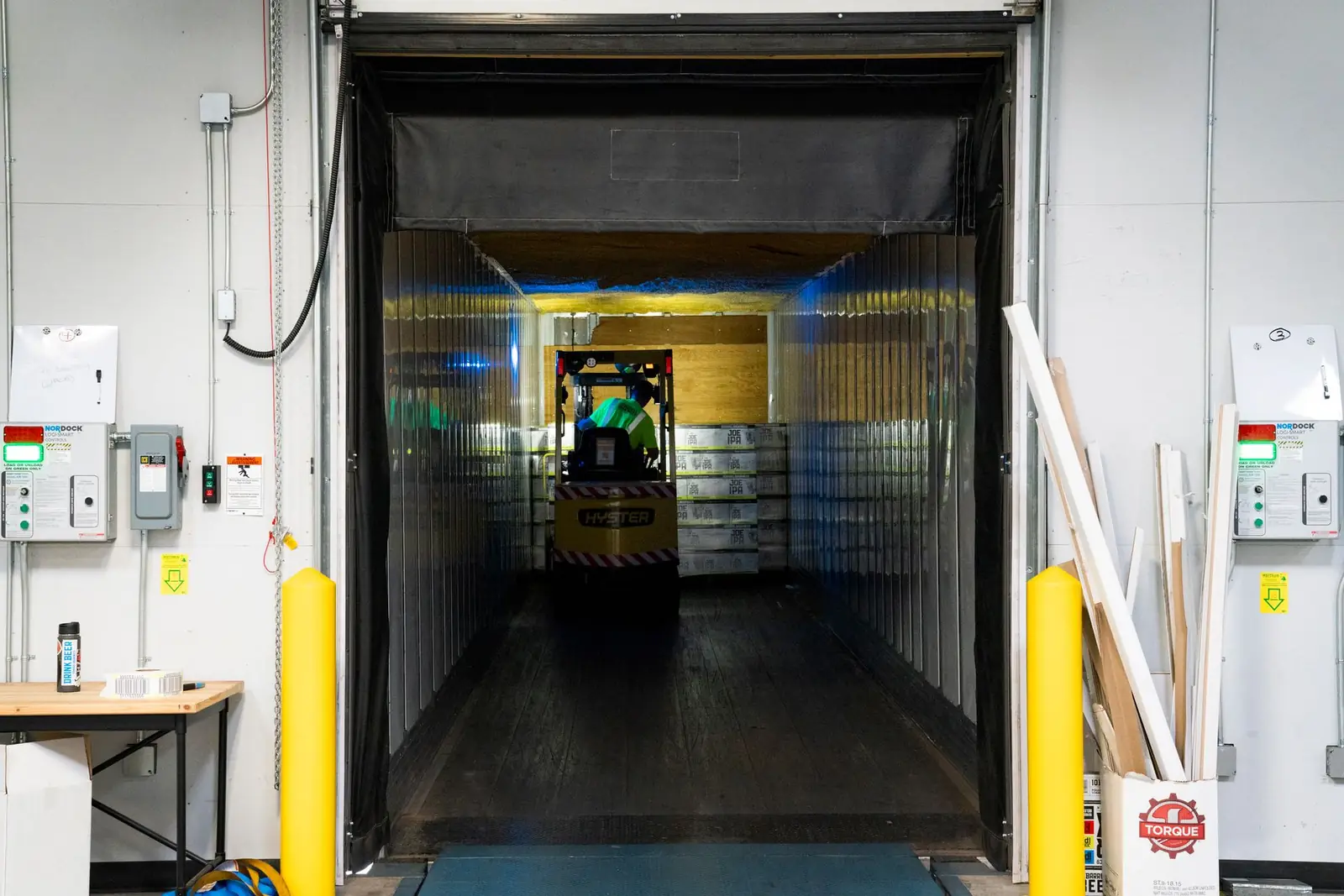 Forklift loading a trailer through a warehouse dock door