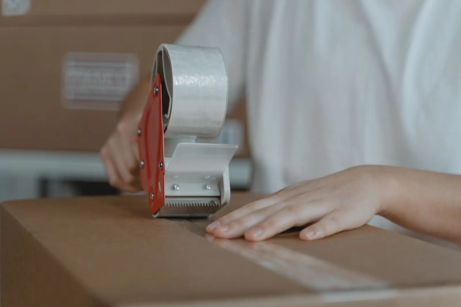 Sealing an order box with a tape gun at a packing station